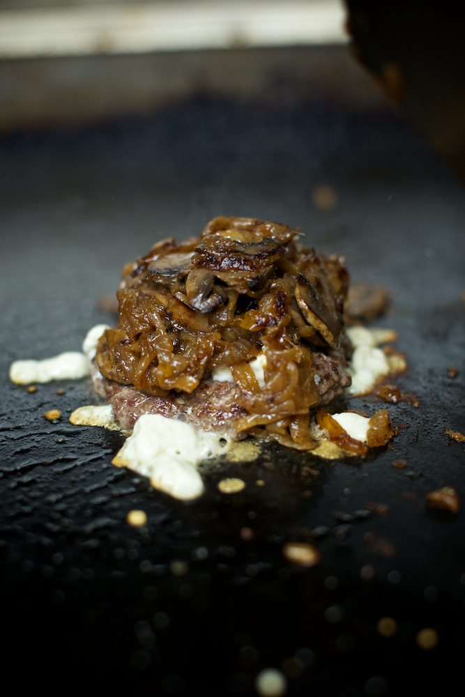 Burger patty with mushrooms on the griddle